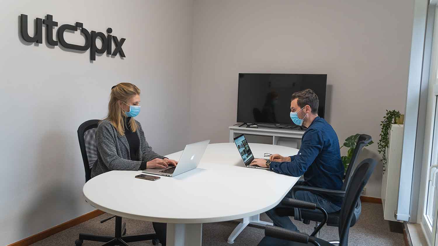 man and woman in a boardroom with facemasks